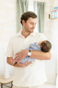 long island newborn photos of dad holding baby in nursery